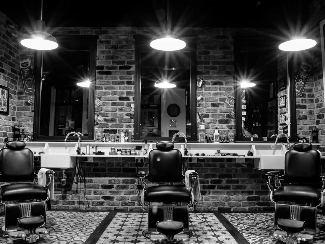 Estação de barbearia com cadeira clássica e parede de tijolo.