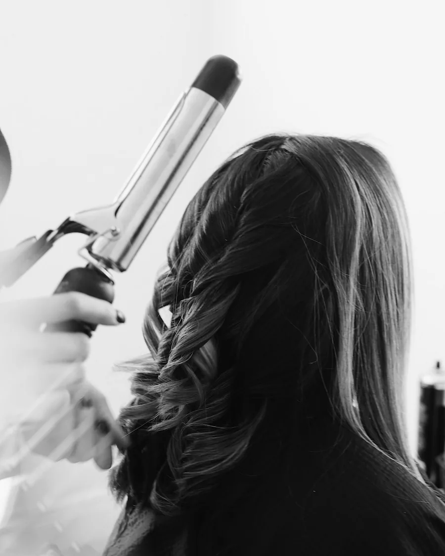 Modelador finalizando cachos em cabelo longo.
